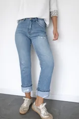 Pantalón de jean corte regular fit en color celeste claro. Presenta un diseño con pequeñas roturas frontales y botamanga con doblez, confeccionado en denim con elastano para mayor flexibilidad y comodidad.