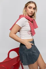 Minifalda de jean azul con diseño de tablas y patrón de rayas verticales finas. Presenta un corte corto y bolsillos laterales.