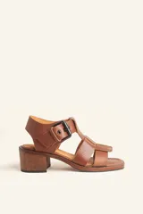 Sandalia de cuero color marrón, con tiras anchas, hebilla lateral y taco ancho de madera.