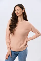 Buzo tejido liso de manga larga con cuello redondo, confeccionado en algodón de tejido grueso. Presenta bordes acanalados en el cuello, los puños y la cintura, con un pequeño detalle de placa metálica en el lateral inferior.