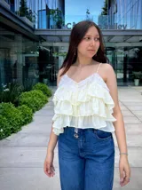 Blusa color amarillo manteca con breteles finos, escote en V con detalle de encaje y volados en capas.