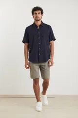 Camisa sport de manga corta, confeccionada en una mezcla de lino y algodón. Presenta cuello clásico, cierre frontal con botones de coco y un bolsillo aplicado en el pecho.