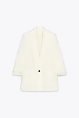 Blazer color blanco hueso, de corte recto y largo, con cuello solapa y un solo botón frontal negro. Las mangas son largas con puños vueltos que revelan un forro interior con estampado de rayas finas.