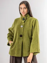 Chaqueta tipo capa confeccionada en paño, con cuello alto, cierre frontal de botones grandes y mangas amplias. Cuenta con bolsillos laterales y forro interior.