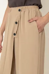 Pantalón ancho color beige, con cintura elastizada, bolsillos laterales y detalle de botones decorativos.