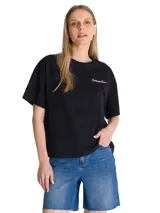 Remera negra de corte boxy y diseño liso, con cuello redondo y mangas cortas. Cuenta con un pequeño logo bordado en contraste sobre el pecho y parche bordado en la manga.