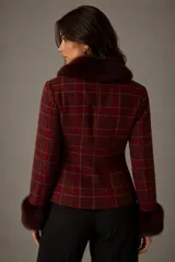 Chaqueta entallada de diseño clásico con estampado de cuadros escoceses en tonos bordó. Presenta cuello y puños con detalle de pelo sintético al tono, cierre frontal con botones y corte ajustado.