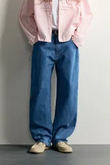Jeans loose fit de tiro medio, confeccionados en denim de algodón color azul con efecto lavado. Presentan diseño de cinco bolsillos, bolsillo plastrón estilo carpintero en la pierna y cierre frontal con cremallera y botón.