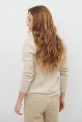Polera de tejido de punto fino en color beige, con cuello alto y mangas largas con puños acanalados.