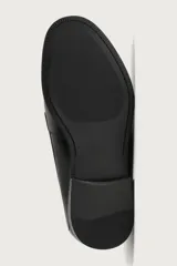 Zapato tipo náutico negro fabricado en piel, con horma redonda, empeine con cordones sutiles y suela a tono con ligero tacón.