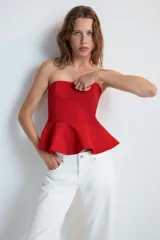 Top rojo sin tirantes, de escote recto y hombros descubiertos, con diseño ajustado en el torso y bajo acabado con peplum. Cierre lateral con cremallera oculta.