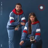 Canguro de felpa azul jean gastado con capucha roja y tiras blancas y rojas en las mangas. Diseño original de autor, corte holgado.