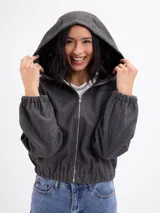 Campera de paño color beige con capucha, cierre frontal completo y mangas largas con puños elásticos. Presenta un diseño corto con ruedo elástico.