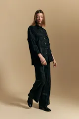Pantalón de corte ancho y silueta relajada, confeccionado en tejido de efecto gamuzado color marrón oscuro. Presenta un diseño de tiro alto con cierre frontal y bolsillos laterales.
