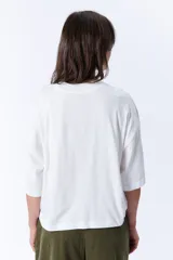 Remera blanca de corte holgado, con cuello alto y mangas 3/4.