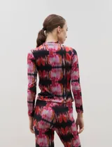 Polera de manga larga con cuello alto, confeccionada en tela sublimada con estampado abstracto en tonos rojizos, rosados y negros.