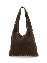 Cartera tipo hobo de gamuza marrón, decorada con tachas metálicas en los bordes y en las asas de hombro.