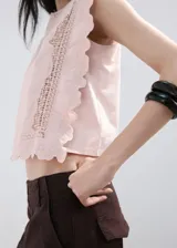 Top de algodón color rosado, con detalles bordados, cuello redondo, mangas cortas y terminaciones festoneadas.