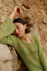 Vestido corto de tejido calado a crochet, color verde militar, con cuello redondo y mangas largas.