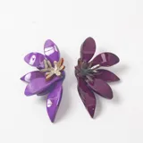 Caravanas con diseño floral en tonos violeta y morado, elaboradas en resina con acabado brillante y centro decorativo metálico.