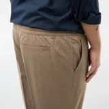 Pantalón de vestir estilo jogger color beige, con corte recto, bolsillos laterales y cierre frontal.