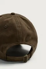 Gorra de seis paneles de color marrón oscuro, confeccionada en tejido de algodón. Cuenta con un diseño bordado en la parte frontal que incluye el texto "TEXAS OUTLAWS", la fecha "1999" y una silueta con estrellas.