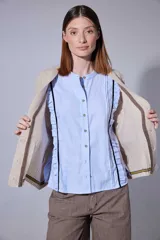 Saco tejido en lambswool con diseño de rombos y trenzas en el frente. Presenta cierre frontal con botones, cuello en V y detalles de rayas en contratono en puños y ruedo. Incluye pin bordado en la manga.