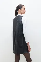 Minivestido negro de cuero ecológico con cuello redondo y sin mangas. Presenta tachas plateadas en el frente y cierre trasero.