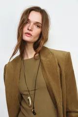 Pack de dos collares. El primero es un collar de cordón negro ajustable con colgantes: una pieza redonda marrón carey, una gota dorada y una gota plateada. El segundo es una cadena fina dorada con un dije alargado dorado y un dije pequeño plateado.