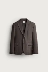 Blazer regular fit de Zara, confeccionada en tejido de lino y lana con diseño a cuadros en tonos marrones y grises. Cuenta con solapas de muesca, cierre frontal de un botón y bolsillos con solapa en la cadera.