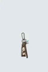 Llavero con diseño de animal print tipo vaca, fabricado en piel con acabado de pelo. Incluye un mosquetón metálico, una tira de cuero lisa y diversos charms decorativos.