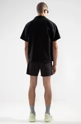 Short de baño negro con cintura elástica y cordón ajustable. Presenta bordados de sirenas en ambas piernas, bolsillos laterales y trasero con cierre. Incluye suspensor de malla fina hipoalergénico.