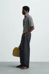 Polo de punto de manga corta con cuello solapa y abertura frontal en forma de V. Presenta un patrón de rayas horizontales finas en blanco y negro, con un acabado texturizado y un calce relajado.