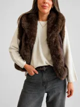 Chaleco acolchado color marrón con diseño matelassé y amplias solapas de piel sintética en tono chocolate. Presenta un corte recto y sin mangas, ideal para superposiciones.