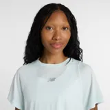 Remera deportiva New Balance de corte relajado y mangas cortas, confeccionada en tejido ligero con tecnología de absorción de humedad. Presenta aberturas laterales y logo reflectante en el pecho.