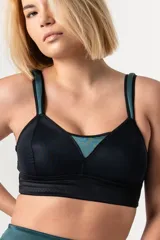 Bralette deportivo reductor negro con breteles anchos magenta regulables y escote alto. Confeccionado en jersey y tela de faja de alta contención.
