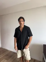 Camisa negra de manga corta, con cuello tipo solapa y textura de punto.