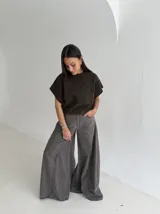 Chaleco tejido de punto color crudo, con cuello redondo y diseño de flor en relieve en el frente. Presenta un corte holgado y mangas cortas con terminación acanalada.