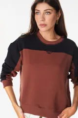 Buzo de cuello redondo con diseño de bloques de color en gris y negro, mangas largas y detalle bordado en el pecho.