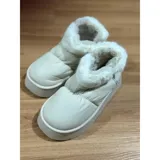 Pantuflas botitas color tostado con diseño acolchado y plataforma, forradas con corderito sintético blanco en el interior y el cuello. Cuentan con una pequeña etiqueta decorativa en el lateral.