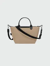 Bolso de mano tipo tote de la línea Le Pliage Energy de Longchamp, en color beige con detalles en negro. Cuenta con asas cortas, solapa frontal con cierre de botón a presión y correa lateral con cordón ajustable.