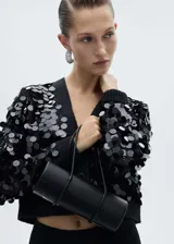 Cardigan negro de punto con cuello en pico y cierre frontal de botones. Presenta un diseño corto con mangas largas y puños elásticos, decorado íntegramente con lentejuelas circulares brillantes.