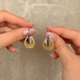 Caravanas de aro con diseño de doble dije en forma de gota, combinando un acabado mate dorado y un acabado brillante plateado.