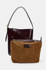 Bolso tipo saca de diseño asimétrico con acabado brillante, asa ajustable con hebilla lateral y cierre mediante botón imán.