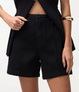 Bermuda midi de jean color negro, con cintura media, cierre de gancho, bolsillos laterales y detalle de costura frontal vertical.