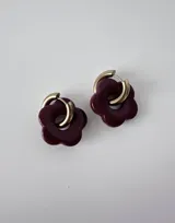 Aros de acero quirúrgico hipoalergénico con argolla dorada y dije colgante en forma de flor color violeta.