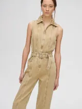 Mono largo de denim azul con corte holgado, recto en las piernas y entallado en el tronco. Tiene cuello camisero, cierre frontal con cremallera y cinturón ajustable.