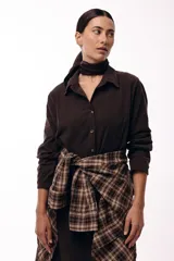 Vestido camisero de color marrón oscuro, con cuello clásico, cierre frontal de botones y mangas largas. Presenta un diseño de corte recto y largo midi.