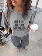 Remera gris con efecto acid wash y diseño oversize. Presenta un estampado frontal con la inscripción "KILLING IN THE NAME OF" y la frase "NOW YOU DO WHAT THEY TOLD YA".