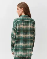 Camisa de corte recto y diseño holgado, con cuello camisero, cierre frontal con botones y mangas cortas. Presenta un estampado de rayas verticales en tonos azul, marrón, celeste y blanco.